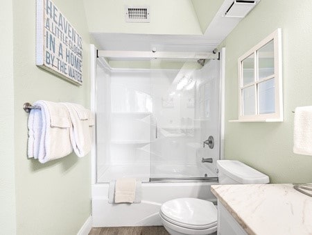 full bathroom featuring vanity, shower / bath combination with glass door, vaulted ceiling, toilet, and wood-type flooring