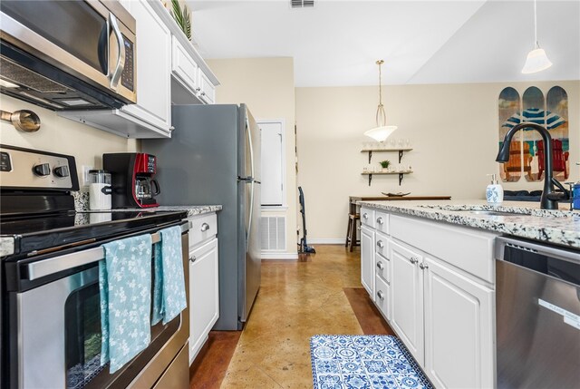 kitchen featuring white cabinets, stainless steel appliances, hanging light fixtures, and light stone counters