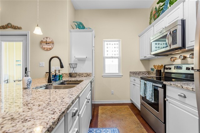 kitchen featuring light stone counters, white cabinets, sink, pendant lighting, and appliances with stainless steel finishes