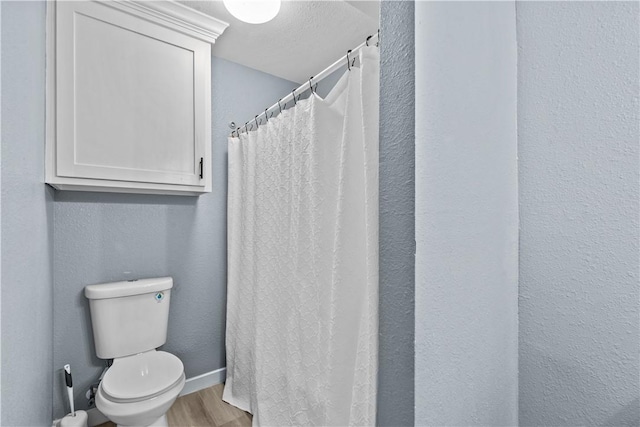 bathroom featuring hardwood / wood-style flooring, toilet, and a textured ceiling