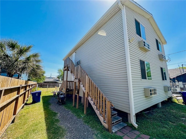 view of side of property featuring a yard and a wall mounted AC