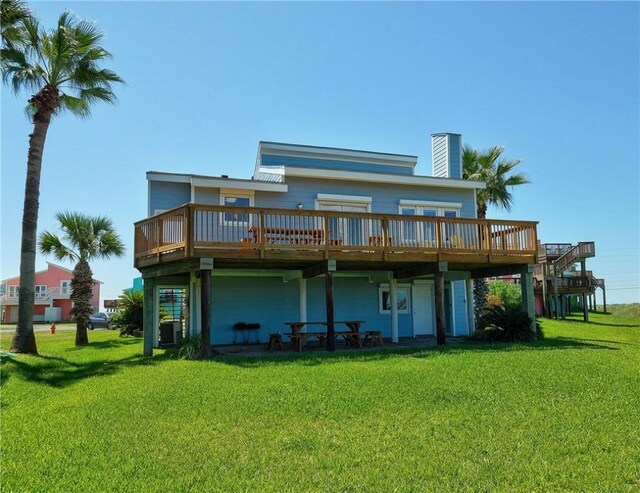 rear view of property with a deck, a yard, and a chimney