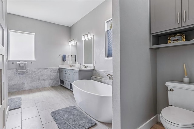 bathroom with double vanity, a sink, a freestanding tub, and toilet