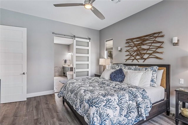 bedroom with baseboards, visible vents, a barn door, and wood finished floors