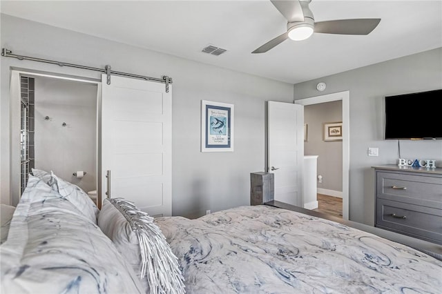 bedroom with ceiling fan, a barn door, baseboards, wood finished floors, and visible vents
