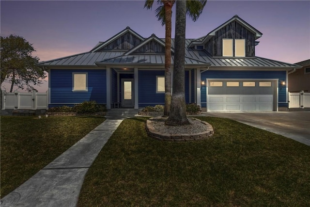 view of front facade with a standing seam roof, covered porch, a yard, and driveway