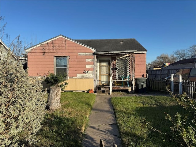 bungalow-style home featuring a front yard and fence