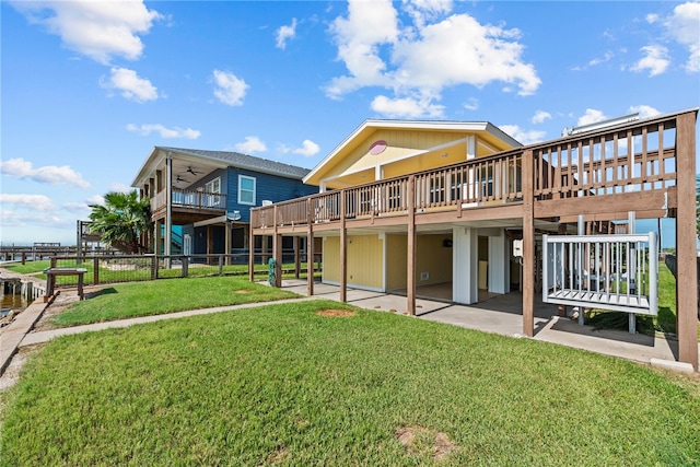 rear view of property featuring a deck, a yard, and a patio area