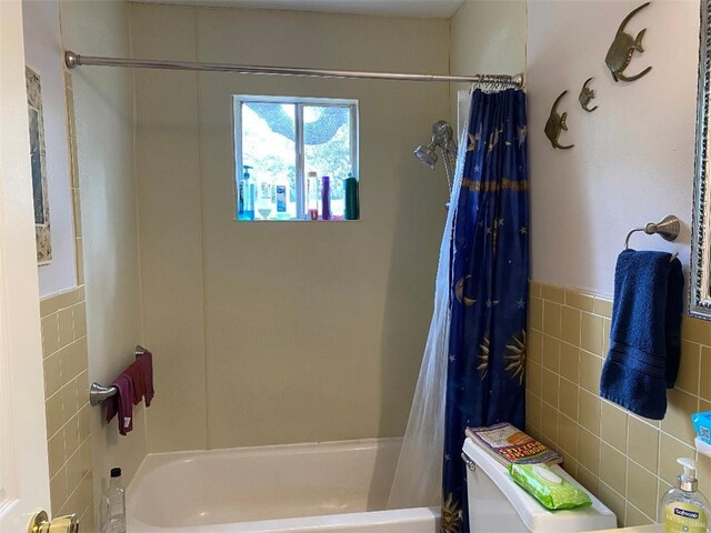 bathroom featuring tile walls and shower / bath combination with curtain