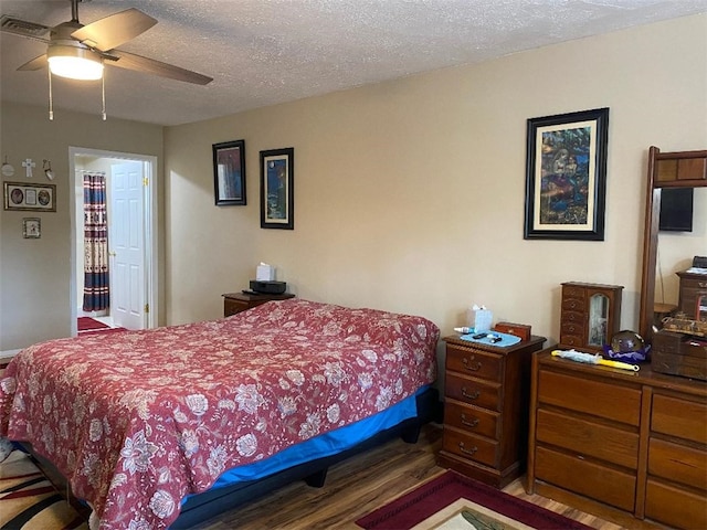 bedroom with hardwood / wood-style floors, ceiling fan, and a textured ceiling