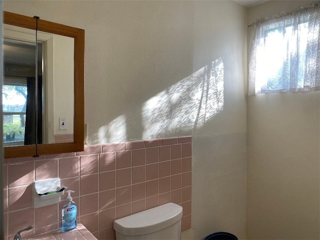 bathroom featuring tile walls, a wealth of natural light, and toilet