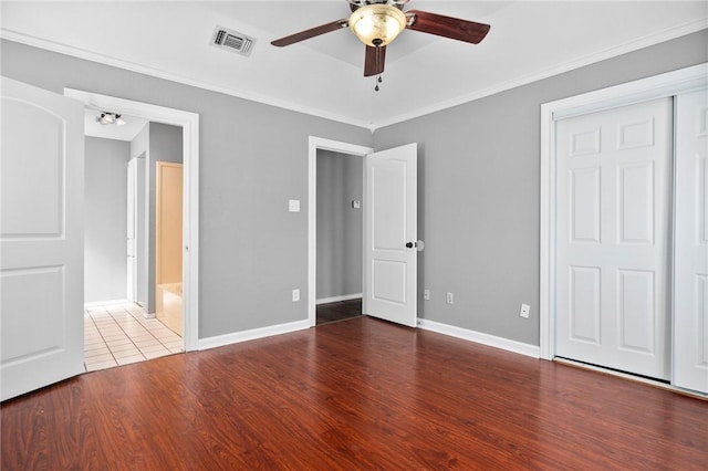 unfurnished bedroom featuring crown molding, visible vents, ceiling fan, wood finished floors, and baseboards