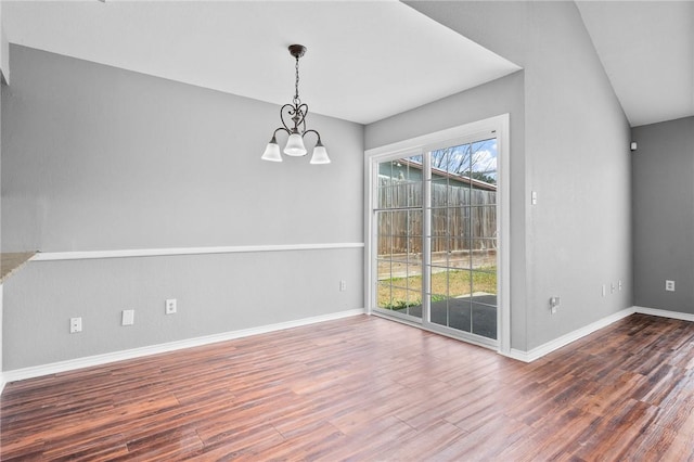 unfurnished dining area with baseboards, a notable chandelier, and wood finished floors