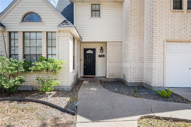 doorway to property featuring a garage, brick siding, and a shingled roof