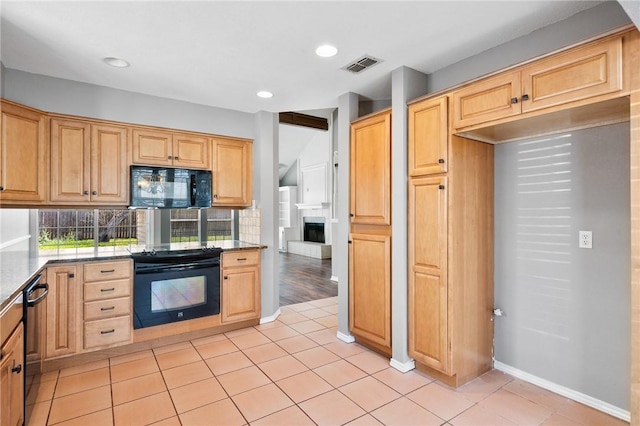 kitchen featuring visible vents, a fireplace with raised hearth, black appliances, and light brown cabinetry