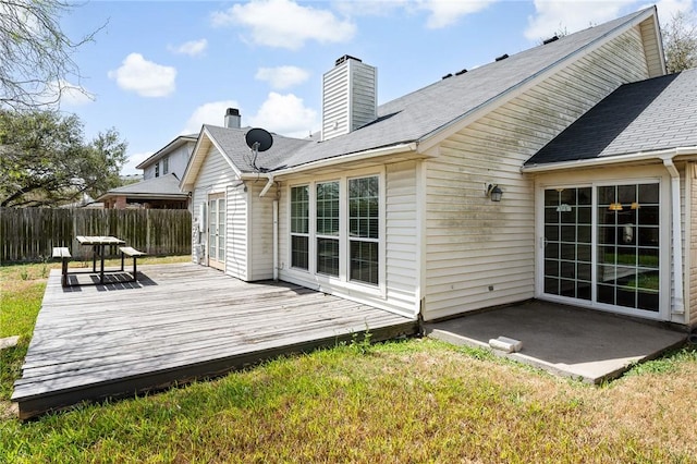 rear view of property featuring a chimney, fence, a deck, and a yard