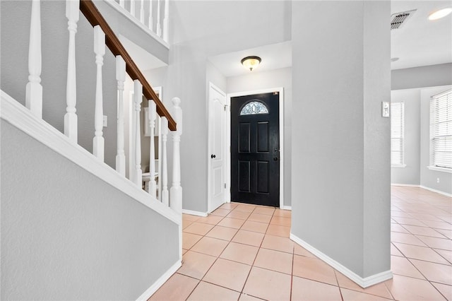 tiled entrance foyer with stairs, visible vents, and baseboards