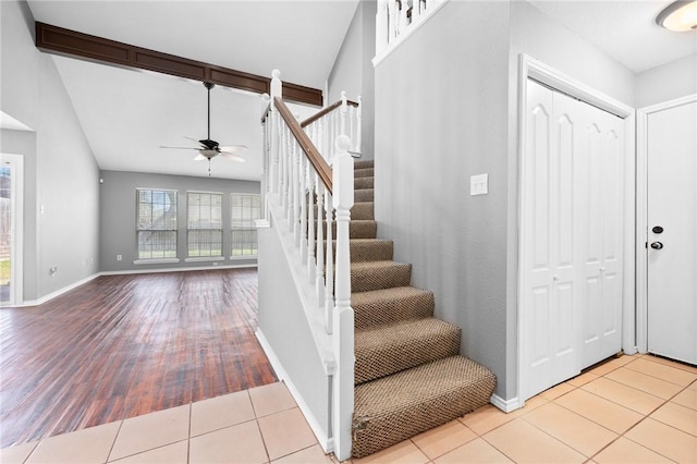 staircase with tile patterned flooring, vaulted ceiling, and baseboards