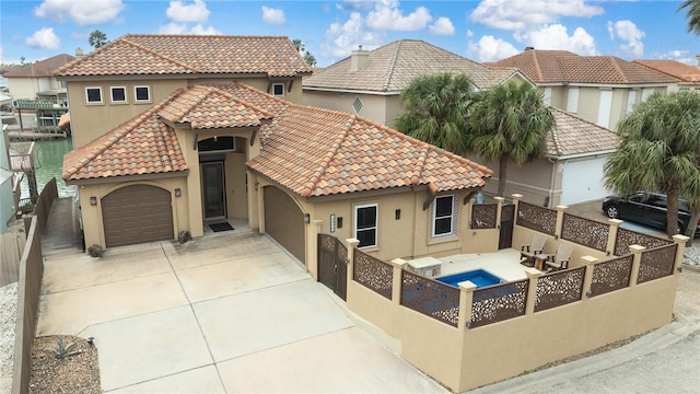 mediterranean / spanish house with a garage, a fenced backyard, a tiled roof, and stucco siding