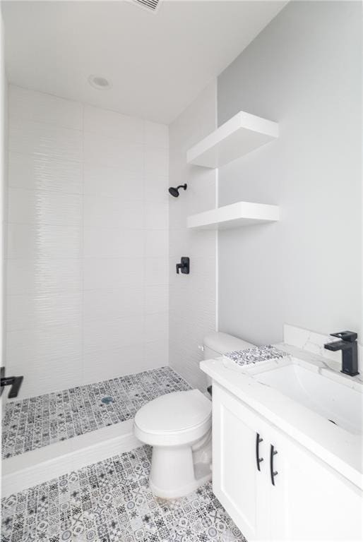 bathroom featuring tiled shower, vanity, and toilet