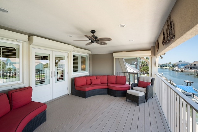 wooden deck featuring an outdoor hangout area, ceiling fan, and a water view