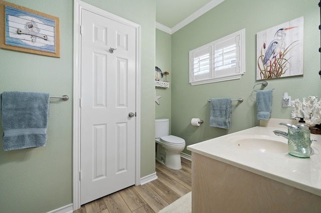 bathroom featuring toilet, wood finished floors, crown molding, baseboards, and vanity