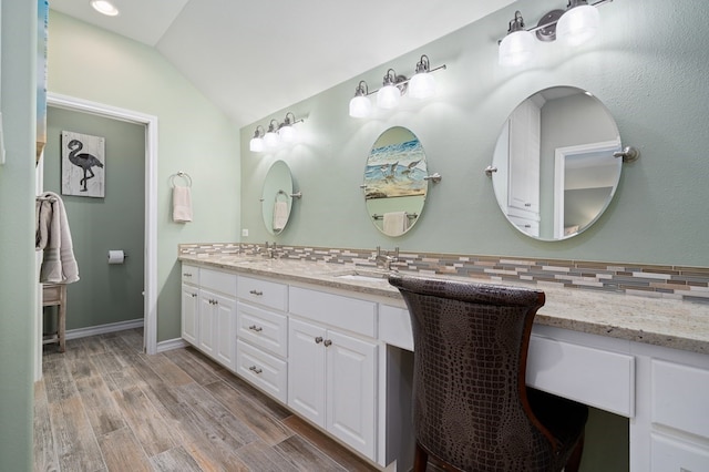 bathroom with hardwood / wood-style flooring, vanity, vaulted ceiling, and backsplash