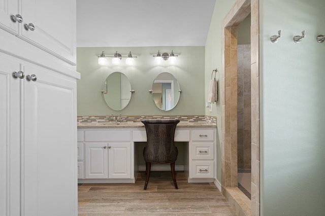 bathroom featuring vanity, wood-type flooring, tasteful backsplash, and a shower