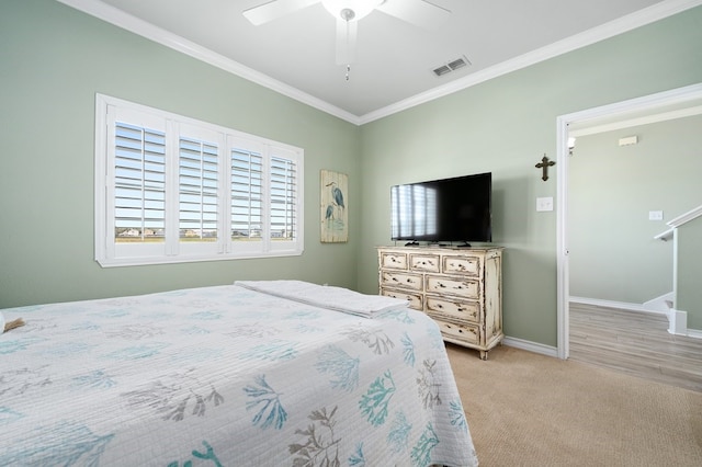 bedroom featuring a ceiling fan, visible vents, baseboards, crown molding, and light colored carpet