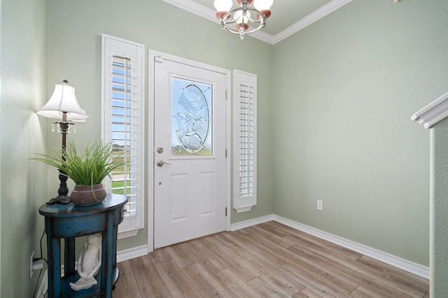 foyer featuring crown molding, a notable chandelier, a wealth of natural light, and light wood-type flooring