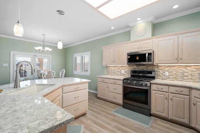 kitchen featuring sink, hanging light fixtures, stainless steel appliances, light hardwood / wood-style floors, and decorative backsplash