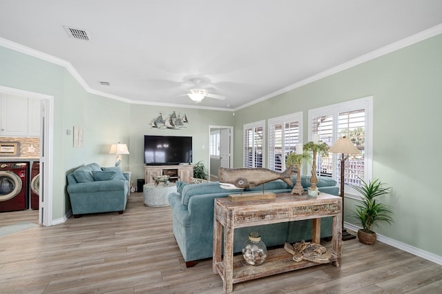 living room featuring light wood-type flooring, visible vents, washing machine and dryer, and crown molding