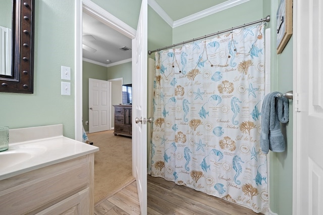 bathroom with crown molding, wood-type flooring, and vanity