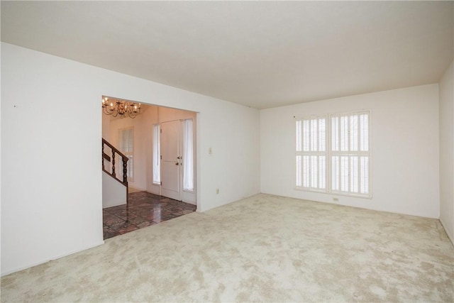 carpeted empty room with a notable chandelier