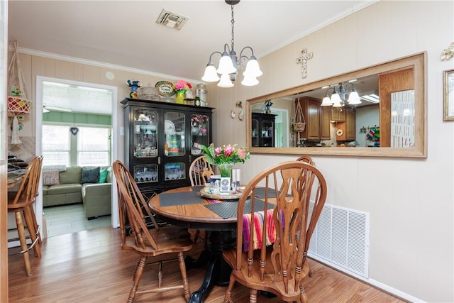 10639 Emmord Loop, Corpus Christi, TX 78410 - dining space featuring a chandelier, ornamental molding, and light wood-type flooring