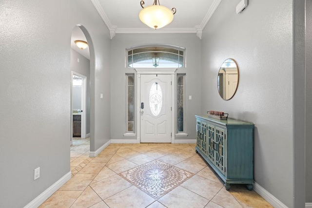 tiled foyer with baseboards, ornamental molding, and arched walkways