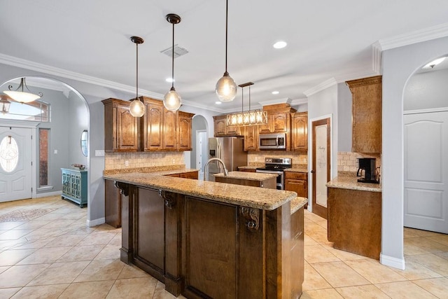 kitchen with appliances with stainless steel finishes, a kitchen island with sink, arched walkways, backsplash, and visible vents