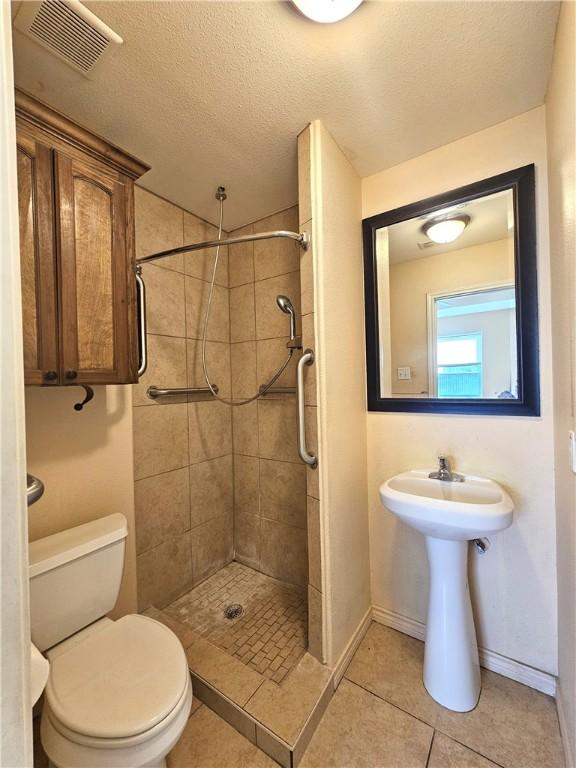 4318 Ivy, Corpus Christi, TX 78415 - bathroom with toilet, a shower stall, tile patterned floors, a textured ceiling, and baseboards