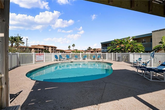 community pool with a patio area and fence