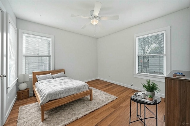 bedroom with light wood-style flooring, baseboards, and multiple windows