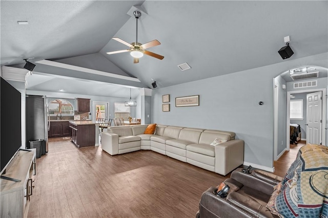 living room featuring ceiling fan with notable chandelier, dark hardwood / wood-style floors, and lofted ceiling