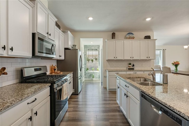 kitchen with stainless steel appliances, a healthy amount of sunlight, a sink, and white cabinets