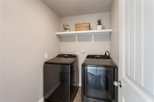 washroom featuring laundry area, washer and clothes dryer, baseboards, and wood finished floors