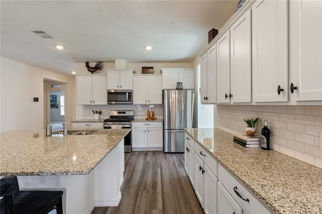 kitchen with appliances with stainless steel finishes, white cabinetry, and a sink