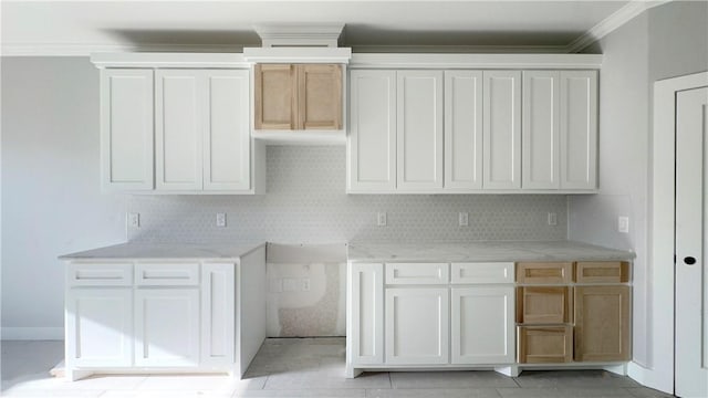 kitchen featuring light stone counters, backsplash, ornamental molding, and white cabinetry