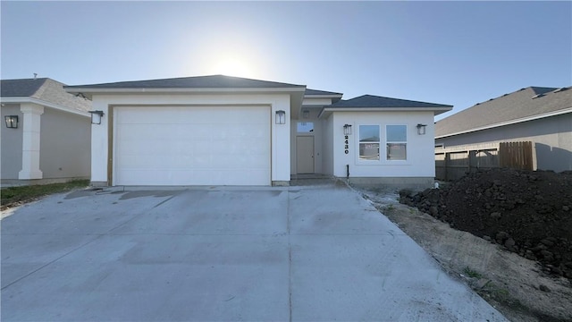 ranch-style home featuring fence, a garage, driveway, and stucco siding