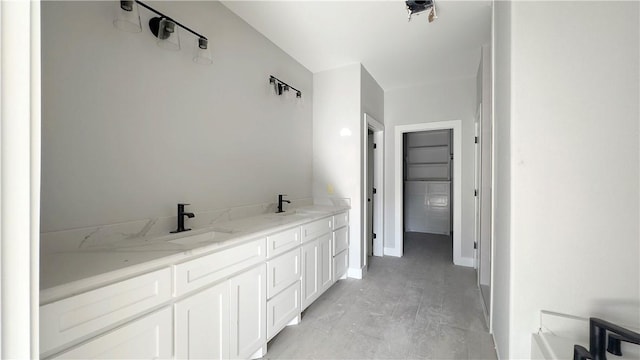 bathroom with double vanity, baseboards, and a sink