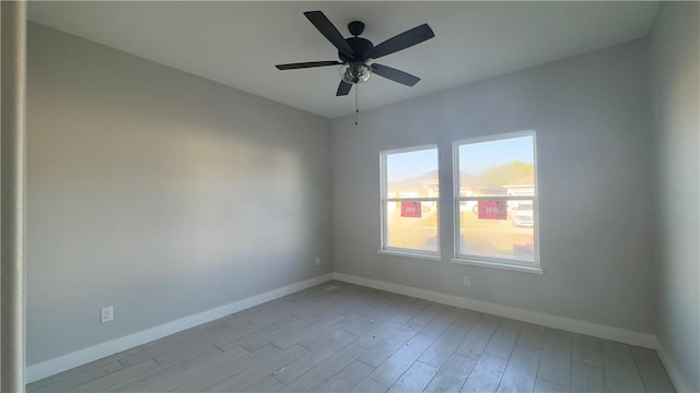 empty room featuring light wood finished floors, ceiling fan, and baseboards