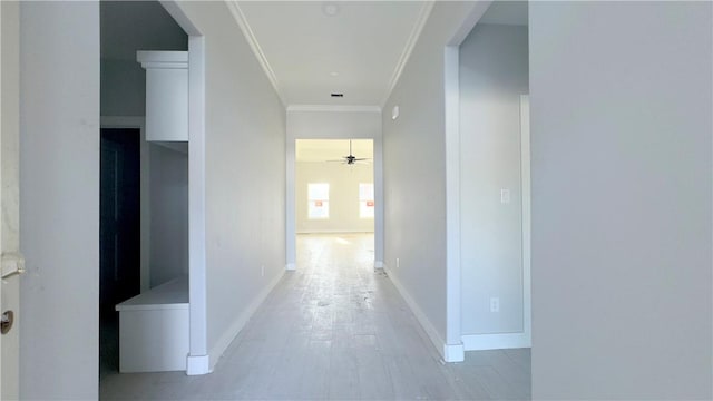 hallway with light wood-type flooring, baseboards, and ornamental molding