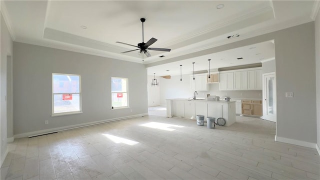 unfurnished living room with light wood finished floors, a ceiling fan, and a tray ceiling